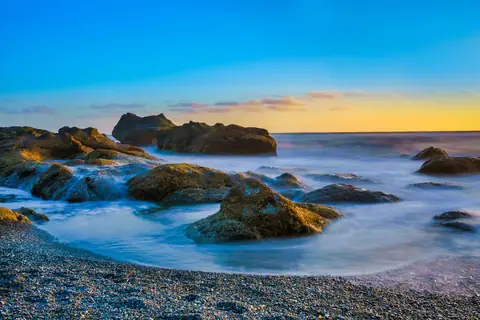 Long exposure waves around rocks at sunset
