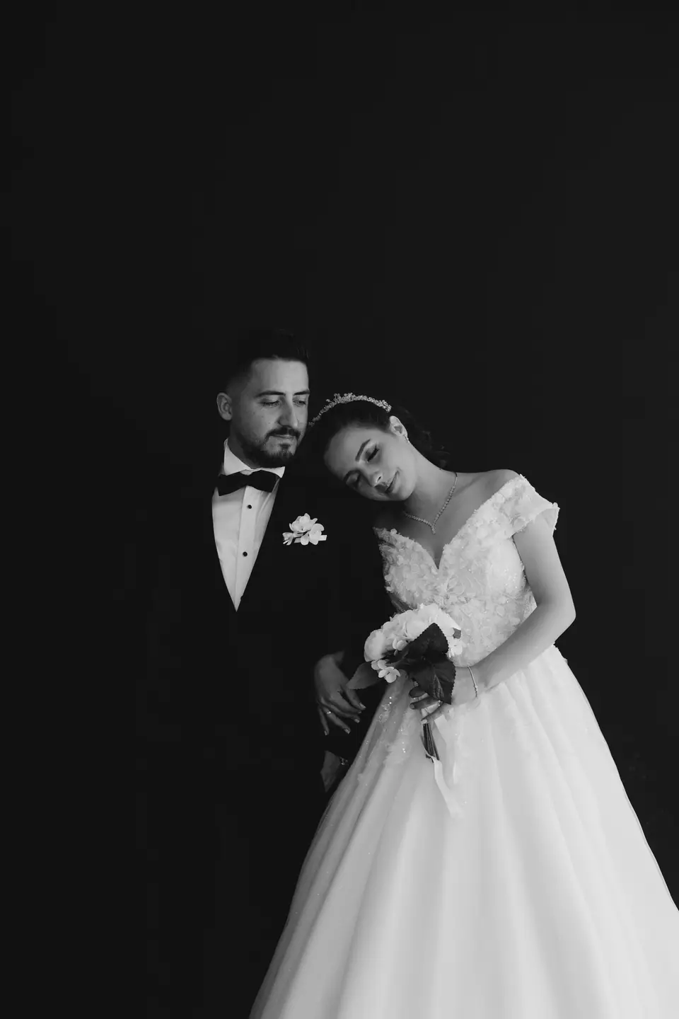 Bride and groom embracing, black and white studio portrait